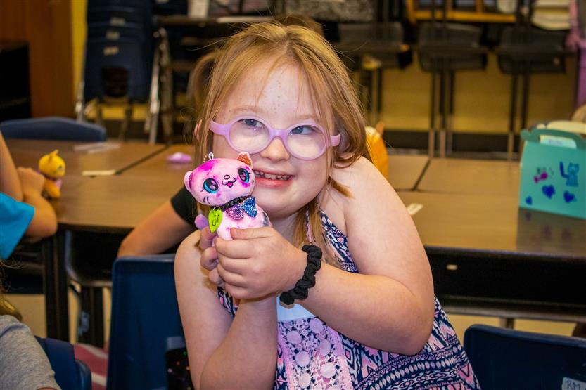 A girl wearing pink glasses smiles
